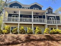 A two-story navy-blue home featuring a large white-columned porch with ceiling fans and manicured landscaping at 4101 Brookview Se Dr, Atlanta, GA 30339