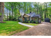 Charming home with new landscaping, inviting walkway, and a detached garage, nestled among mature trees at 1186 Thomas Rd, Decatur, GA 30030