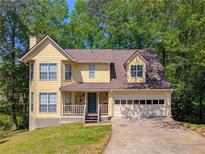 Charming yellow two-story home featuring an attached garage, a stone porch, and a well-maintained lawn at 1166 Memory Ln, Lawrenceville, GA 30044