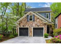 Stone front facade with a two-car garage, dark doors and shutters, and manicured landscaping at 1048 Standard Ne Dr, Brookhaven, GA 30319