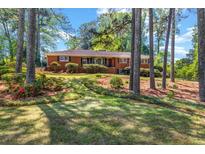 Charming brick ranch-style home featuring a well-maintained front yard with mature trees and landscaping at 2396 Midvale Cir, Tucker, GA 30084
