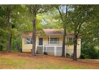 Charming yellow home with a cozy front porch and lush green trees surrounding the property at 21 Misty Hollow Ct, Euharlee, GA 30145