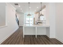 Bright kitchen features an island, stainless steel appliances, and hardwood floors at 103 Iveybrooke Ln # 56, Alpharetta, GA 30009