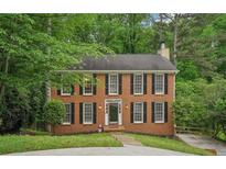 Charming two-story brick home with black shutters surrounded by lush landscaping at 2895 Shurburne Dr, Alpharetta, GA 30022