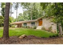Charming home featuring a stone facade, updated windows, landscaped yard, and a welcoming, bright orange front door at 4228 Durham Cir, Stone Mountain, GA 30083