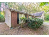 Brick and vinyl exterior with trimmed windows and manicured landscaping at 3856 Vine Stone Dr, Lithonia, GA 30038