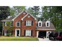Charming two-story brick home with black shutters, mature trees, and an attached two-car garage at 1030 San Lacinto Ln, Lawrenceville, GA 30043
