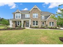 Beautiful two-story home featuring a brick facade, inviting front porch, and a well-manicured lawn at 2127 Harmony Dr, Canton, GA 30115