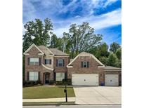 Charming brick two-story home with manicured lawn and attached two-car garage at 1710 Ashbury Park Dr, Hoschton, GA 30548