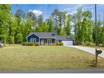 Charming blue home with a well-manicured lawn and attached garage, perfect for suburban living at 60 Water Oak Trl, Covington, GA 30014
