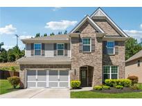 Charming two-story home featuring a brick facade, arched entryway, and a well-manicured lawn at 4050 Danbury Farms Dr, Cumming, GA 30040