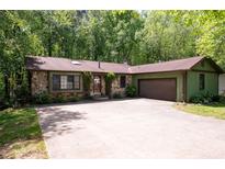 Charming stone and wood exterior with a spacious driveway and lush green trees at 247 Shallowford Nw Rd, Kennesaw, GA 30144