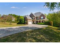 Beautiful two story brick home with red shutters and a long driveway approaching the attached two-car garage at 4828 Planters Walk, Douglasville, GA 30135