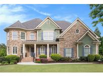 Charming two-story home with a manicured lawn, stone accents, and inviting front porch at 3820 Preserve Crossing Ln, Cumming, GA 30040