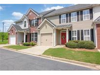 Charming townhome with a red front door, attached garage, and well-maintained landscaping at 2557 Avery Park Cir, Doraville, GA 30360