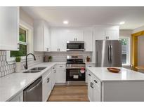 Modern kitchen featuring white cabinets, stainless steel appliances, and quartz countertops at 2358 Larchwood Sw Rd, Atlanta, GA 30310