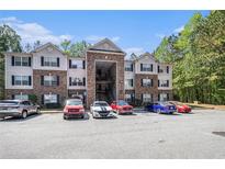 View of a brick and siding apartment building with ample parking and mature landscaping at 3235 Fairington Dr, Lithonia, GA 30038