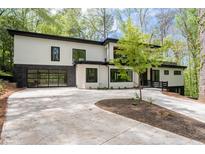 Modern home featuring a black framed glass garage door, white siding, and a curved concrete driveway at 4366 Skyland Ne Dr, Atlanta, GA 30342