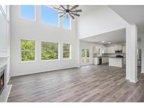 Bright, open living room boasts high ceilings, fireplace, modern ceiling fan, and view of wooded yard at 881 Springs Crest Dr, Dallas, GA 30157