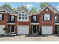 Charming brick townhouses featuring attached garages, well-kept landscaping, and inviting front doors at 215 Morris Ln, Woodstock, GA 30188