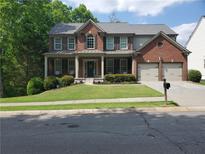 Inviting two-story home with a brick facade, covered porch, manicured lawn, and a two-car garage at 101 Brendylynn Trce, Woodstock, GA 30188