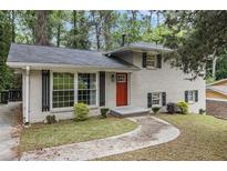 Charming home featuring a painted brick facade, complemented by a bright red front door and well-manicured landscaping at 2724 Quincy Ln, Decatur, GA 30034