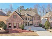 Stunning brick and stone home featuring a symmetrical facade, manicured landscaping, and a spacious driveway at 4802 Moon Chase Dr, Buford, GA 30519