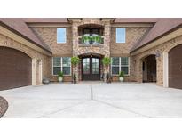 Beautiful brick home featuring arched doorways, a balcony, a well-maintained yard, and a spacious driveway at 401 Sara Ct, Loganville, GA 30052