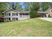 Charming two-story home featuring a spacious front yard, carport, and a welcoming red front door at 3500 Finesse Dr, Decatur, GA 30032
