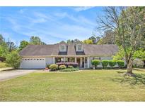 Charming single-story home with a well-manicured lawn, dormer windows, and a welcoming front porch at 65 Macadamia Ct, Covington, GA 30016