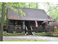 Charming log cabin-style home with a covered front porch and stone chimney, perfect for rustic living at 6503 Old Macon Hwy, Rex, GA 30273