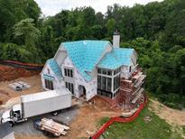 A new home under construction featuring large windows, a brick chimney, and a bright blue roof covering at 469 Emily Reed Ln, Atlanta, GA 30342