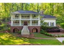 Charming two-story home with double porches, brick accents, and landscaped front yard surrounded by lush greenery at 4094 Norton Se Pl, Smyrna, GA 30082