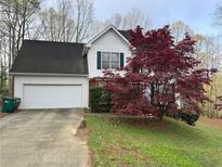 Charming two-story home with an attached garage and a well-maintained front yard with a beautiful red tree at 602 Springharbor Dr, Woodstock, GA 30188