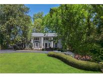 Charming two-story home with landscaped front yard, circular driveway, and lush, mature trees at 1011 W Paces Ferry Nw Rd, Atlanta, GA 30327