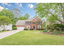 Beautiful two-story brick home with a lush green lawn and meticulously maintained landscaping at 745 Amberton Close, Suwanee, GA 30024