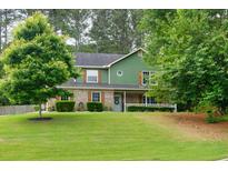 Charming two-story home featuring a covered front porch, manicured lawn, and mature trees offering curb appeal at 3987 Ivory Gables Pl, Buford, GA 30519