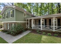 Charming two-story home featuring a brick facade, green siding, and a welcoming front porch at 4628 Mountain Creek Ne Dr, Roswell, GA 30075