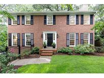 Charming brick home featuring black shutters, a manicured lawn, and lush landscaping at 535 Silver Pine Trl, Roswell, GA 30076