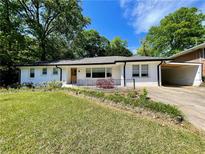 Charming one-story white brick home with a well-maintained lawn, inviting curb appeal, and attached carport at 2682 Pineland Ave, Atlanta, GA 30340