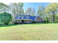 Charming brick home featuring a covered front porch and expansive, well-manicured lawn at 5800 S Richland Creek Rd, Buford, GA 30518