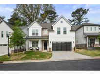 Charming two-story home featuring white siding, black trim, inviting front porch, and a two-car garage at 763 Arrendale Dr, Marietta, GA 30064