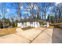 Charming single-story home boasts a welcoming carport, a freshly painted exterior, and an expansive concrete driveway at 932 Mount Airy Sw Dr, Atlanta, GA 30311