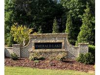 Stone sign for Emerald Lake with landscaped flower beds, shrubbery, and mature trees in the background at 535 Emerald Pkwy, Sugar Hill, GA 30518