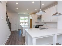 Bright kitchen with white cabinetry, quartz countertops, stainless steel appliances, and stylish pendant lighting at 105 Iveybrooke Ln # 57, Alpharetta, GA 30009