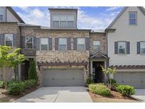 Charming townhome with a stone and brick facade, inviting curb appeal, and a two-car garage at 1074 Heyward Way, Alpharetta, GA 30009