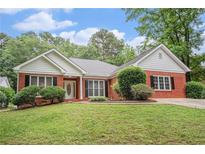 Charming brick home with a well-manicured lawn, complemented by lush greenery and flowering bushes at 1721 Druids Se Xing, Conyers, GA 30013
