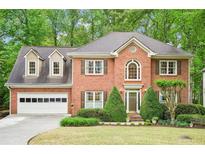 Charming two-story brick home featuring a manicured lawn and attached two-car garage at 1894 Whitehawk Ct, Lawrenceville, GA 30043