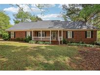 Charming single-story brick home featuring a welcoming front porch and a well-maintained lawn with mature trees at 2301 Sharon Se Ct, Conyers, GA 30013