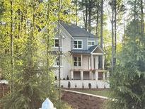 Charming two-story home with a brick facade and inviting front porch surrounded by mature trees at 1005 Liberty Springs Dr, Woodstock, GA 30188